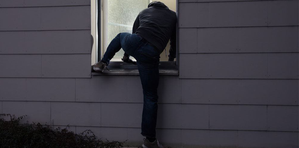 Someone breaking into a house through an open window